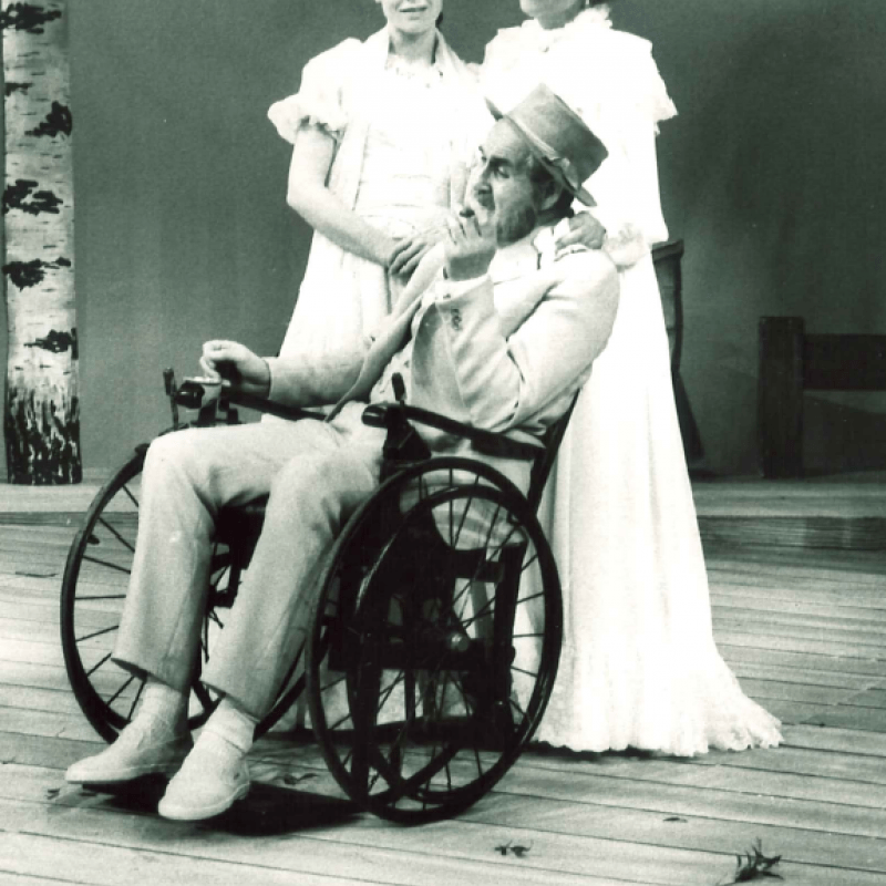 En man sitter i rullstol som leds av en kvinna sam samtalar med en annan yngre kvinna.
