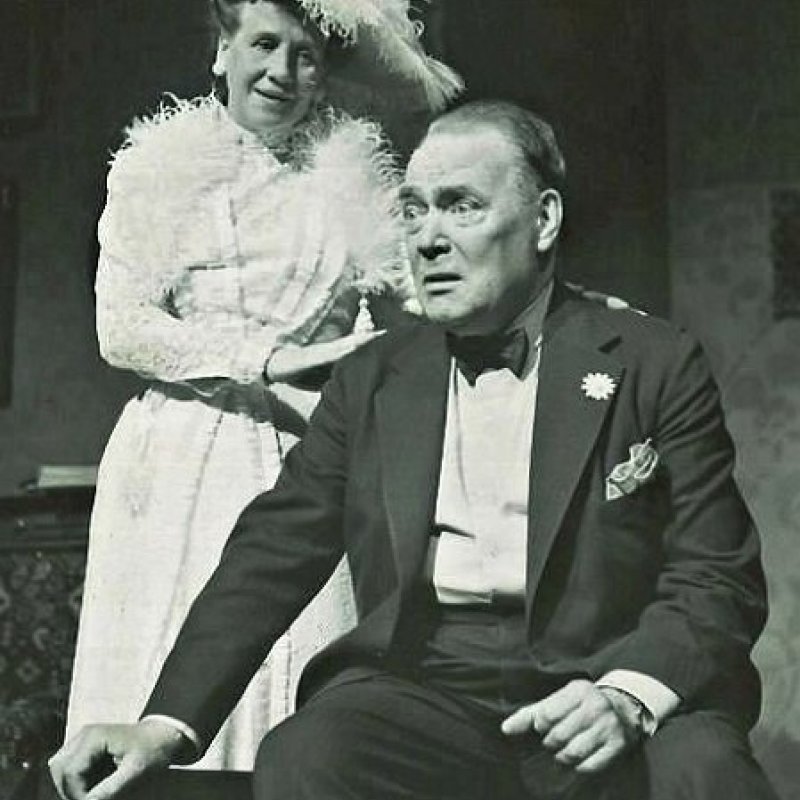 kvinna i hatt bredvid sittande man i smoking