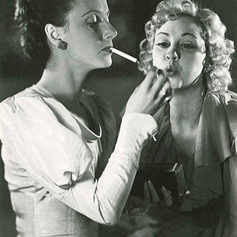 två kvinnor tänder en cigarett