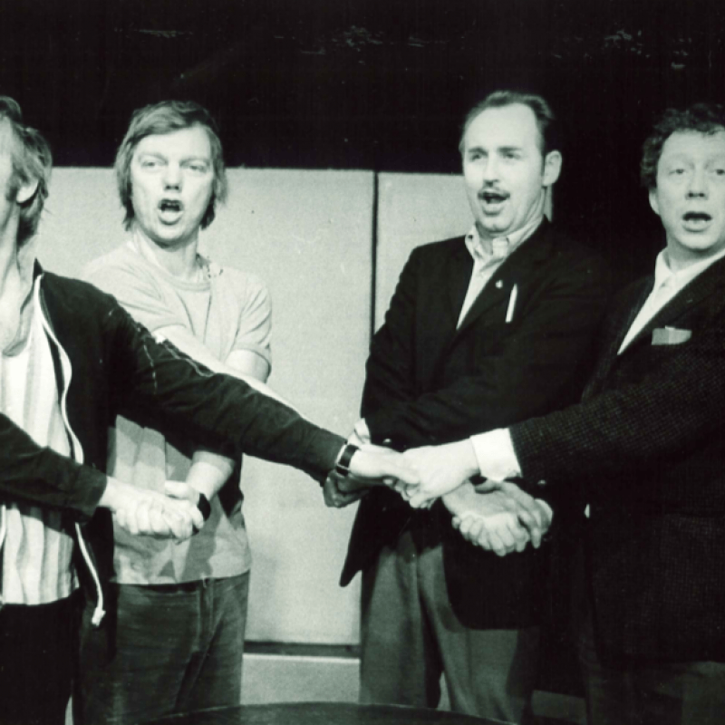 fyra personer håller händer och sjunger