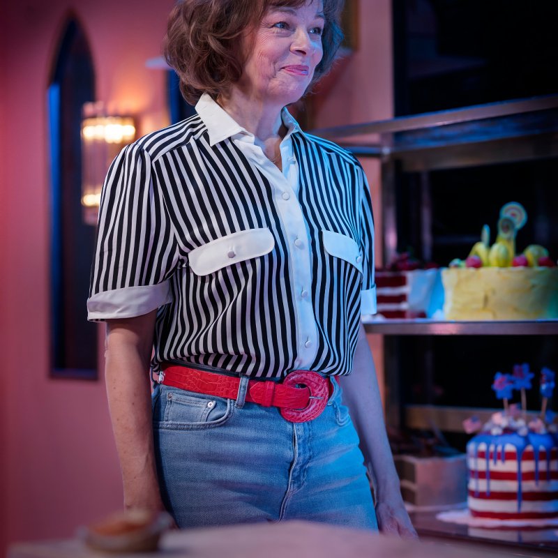En kvinna i skjorta och jeans vid en köksbänk