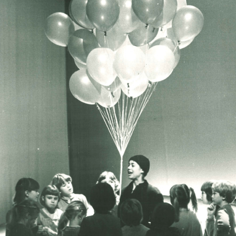 Person med ballonger omringad av barn