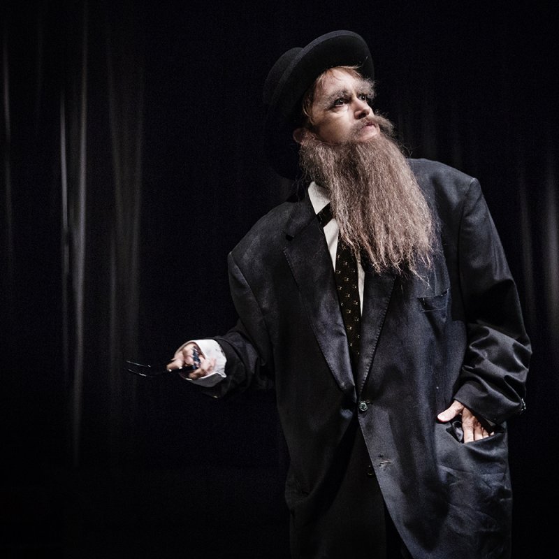 En rabbin med klassisk judisk kostym och hatt blickar uppåt.