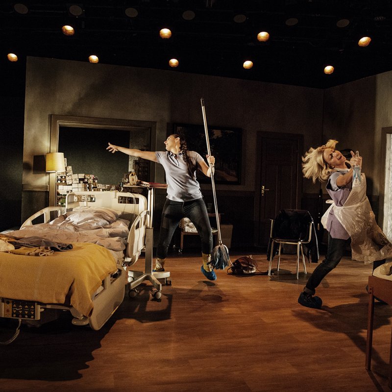 Frida och Ljiljana dansar runt i en lägenhet bredvid en sjukhussäng