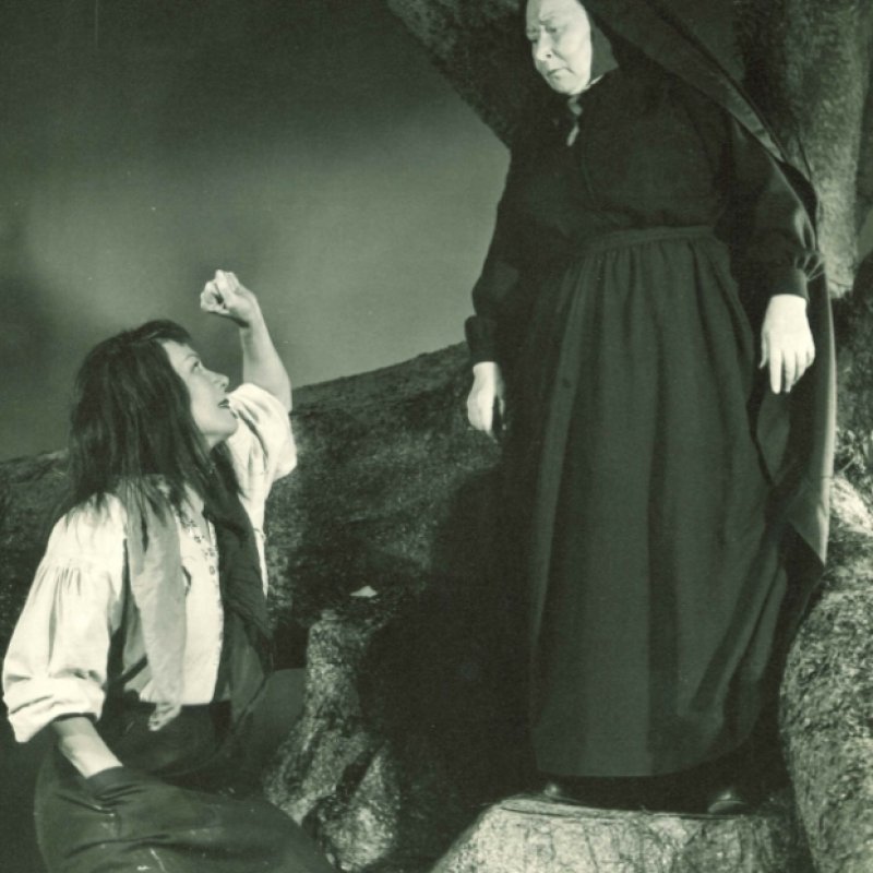 person på knä framför svartklädd kvinna