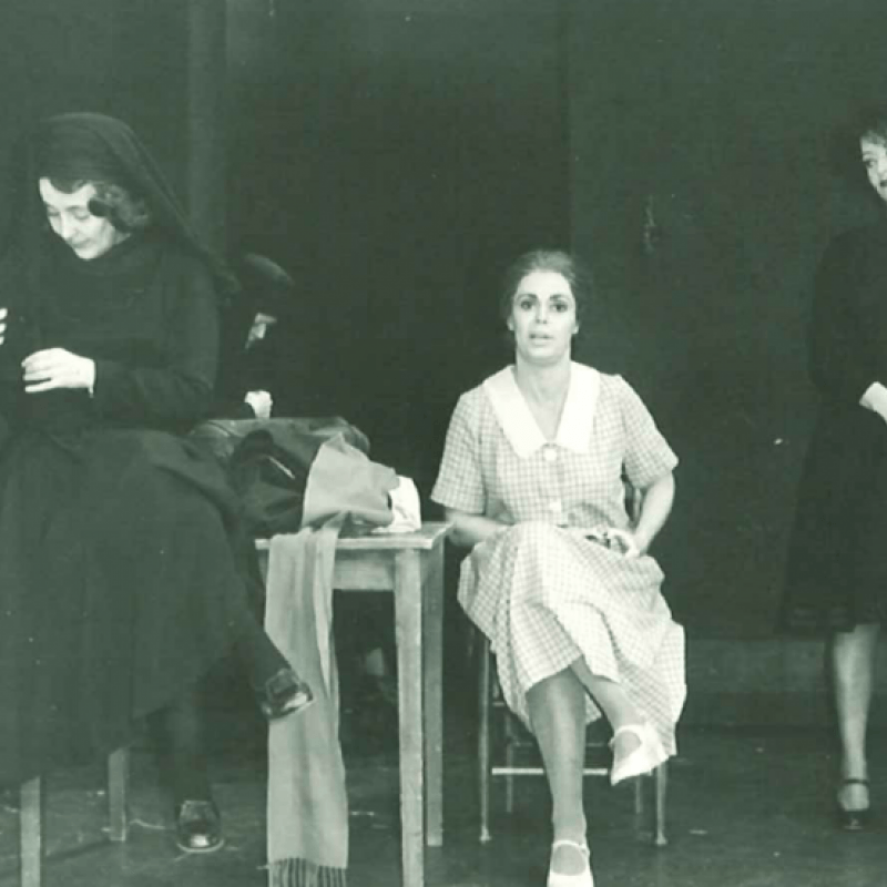 Tre nunnor och en vitklädd kvinna runt ett bord