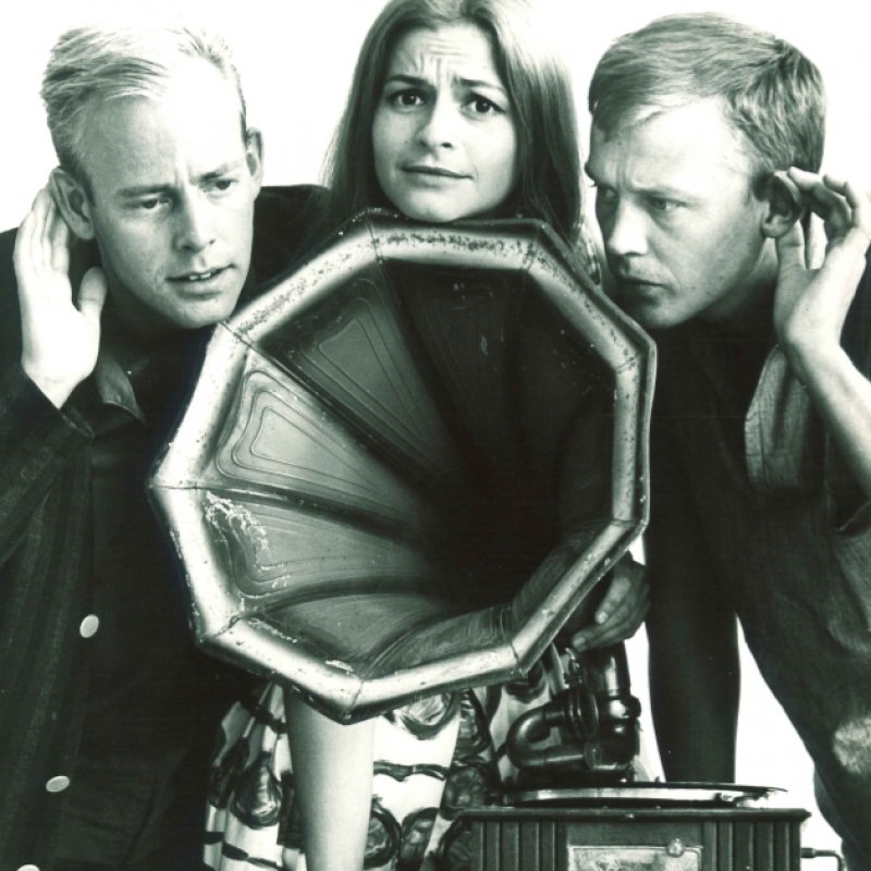 tre personer lyssnar på en gramofon