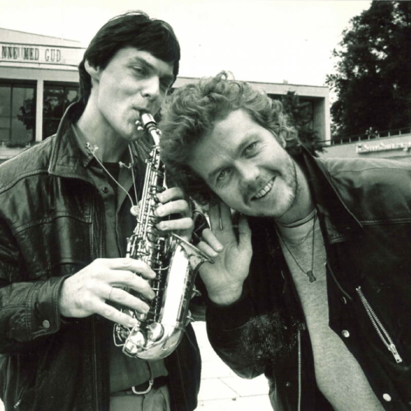 Porträtt av två män utanför Storan. En spelar saxofon