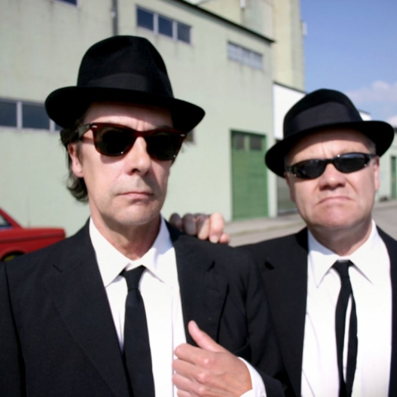 Två män i kostym, solglasögon och hatt.