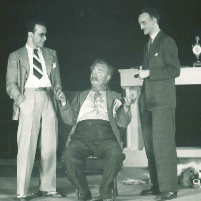 En man sitter emellan två yngre stående män