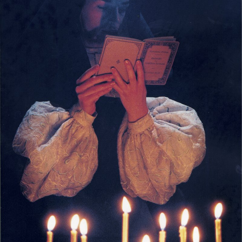 En nunna läser vid tända ljus.