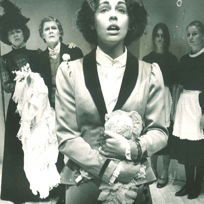 Kvinna med docka framför fyra personer