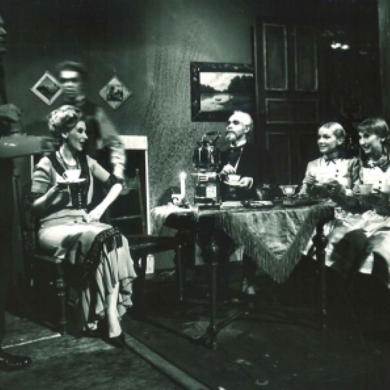 Grupp kvinnor sitter och fikar kring ett runt bord i vardagsrumsmiljö