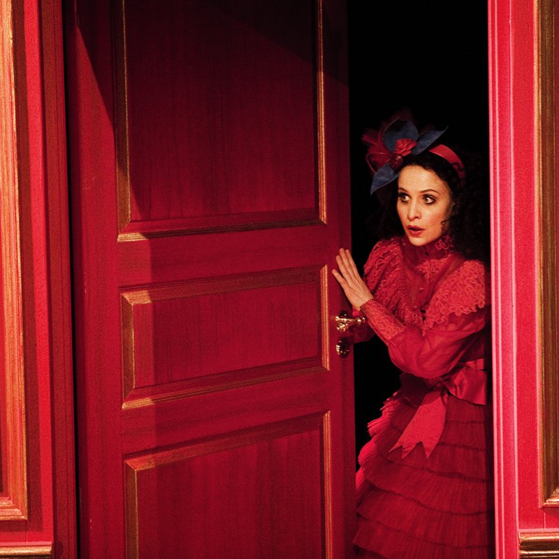 Kvinna i rött öppnar en röd dörr