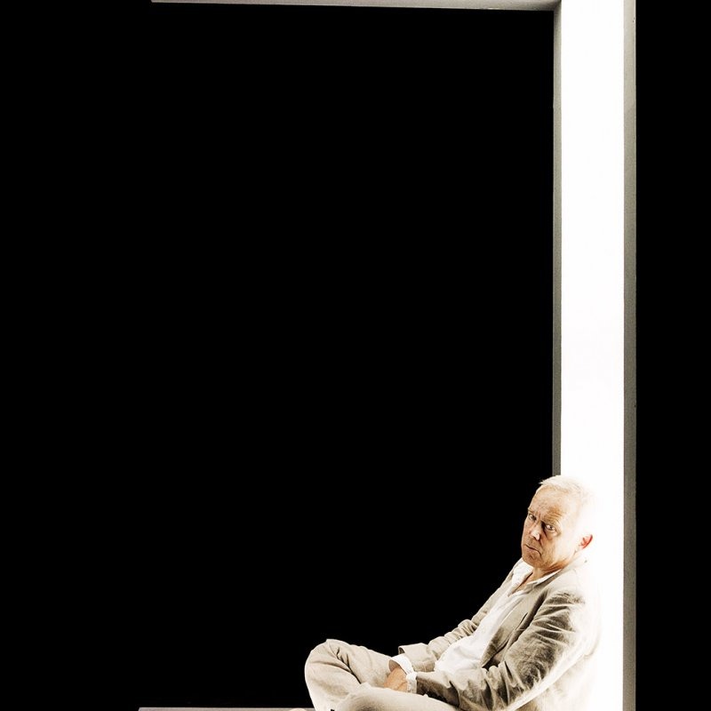 En man sitter mot en lysande vägg