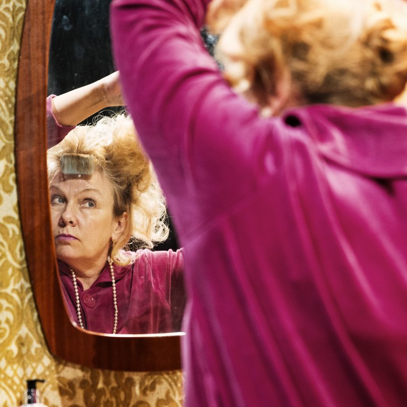 Kvinna gör sig i ordning framför spegeln 