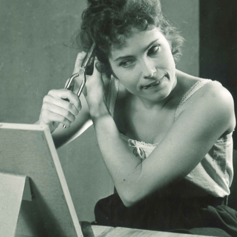 kvinna klipper sitt eget hår framför spegel