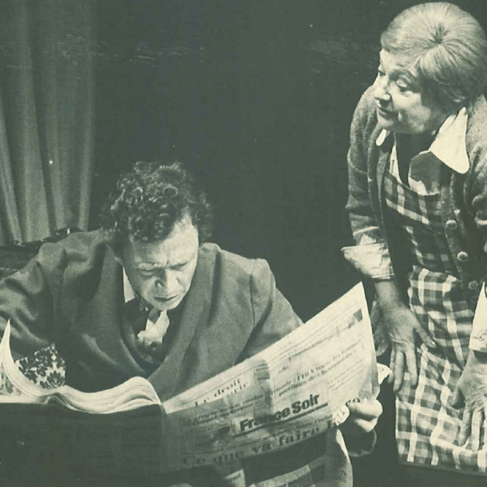 Man läser tidning vid bord bredvid kvinna