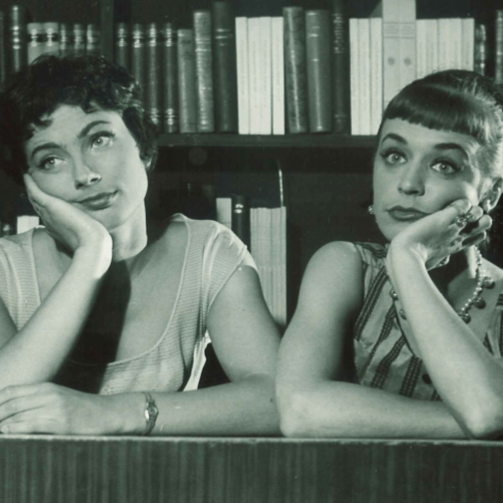 två kvinnor tittar uttråkat bort