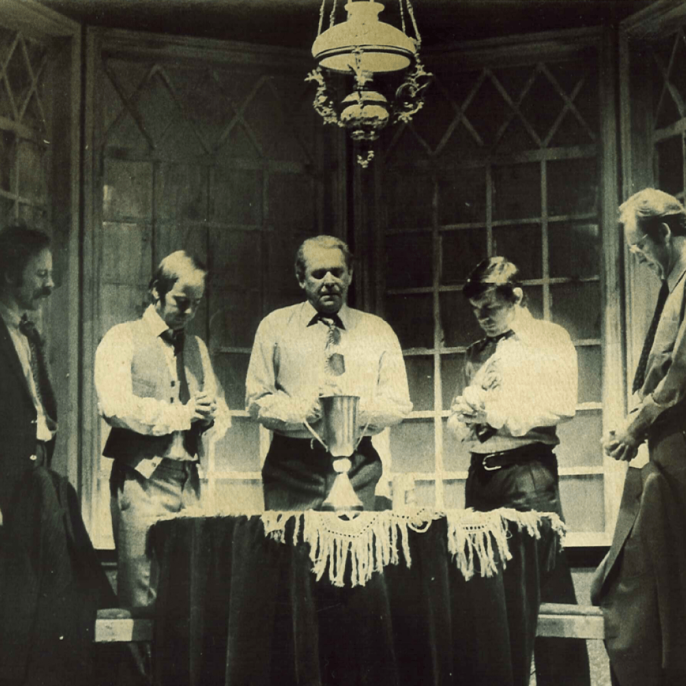 Fem män runt en pokal på ett bord