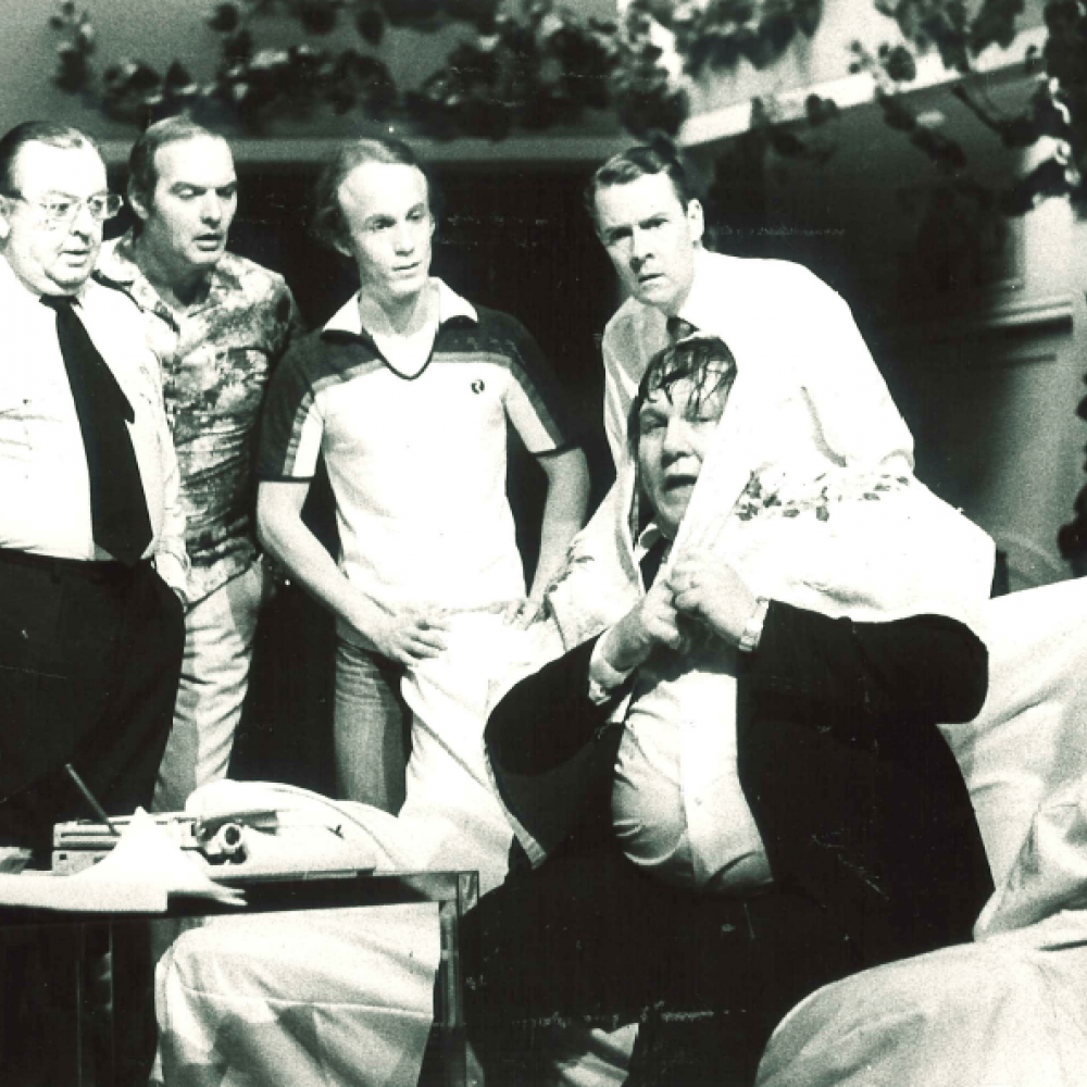 Fyra män stirrar på en femte som sitter blöt i en soffa med en tidning över huvudet