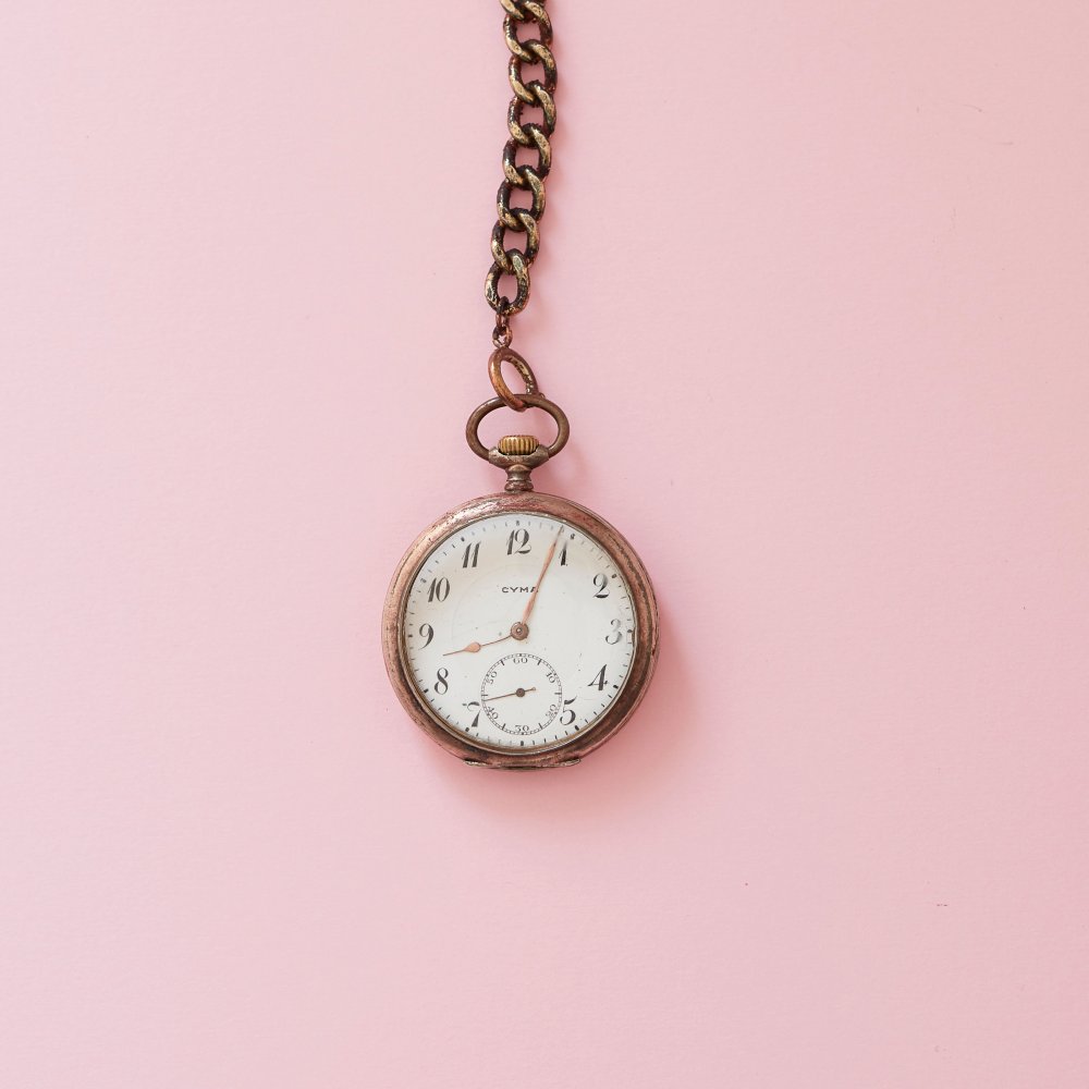En antik klocka på rosa bakgrund.