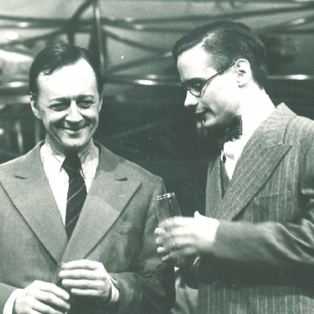 Två män i kostymer dricker och ler