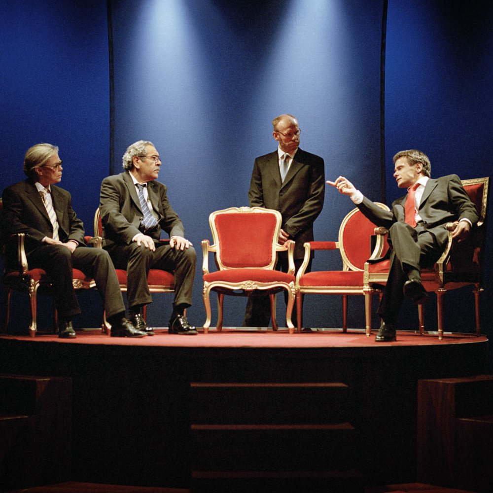 Fyra personer debatterar på röda stolar