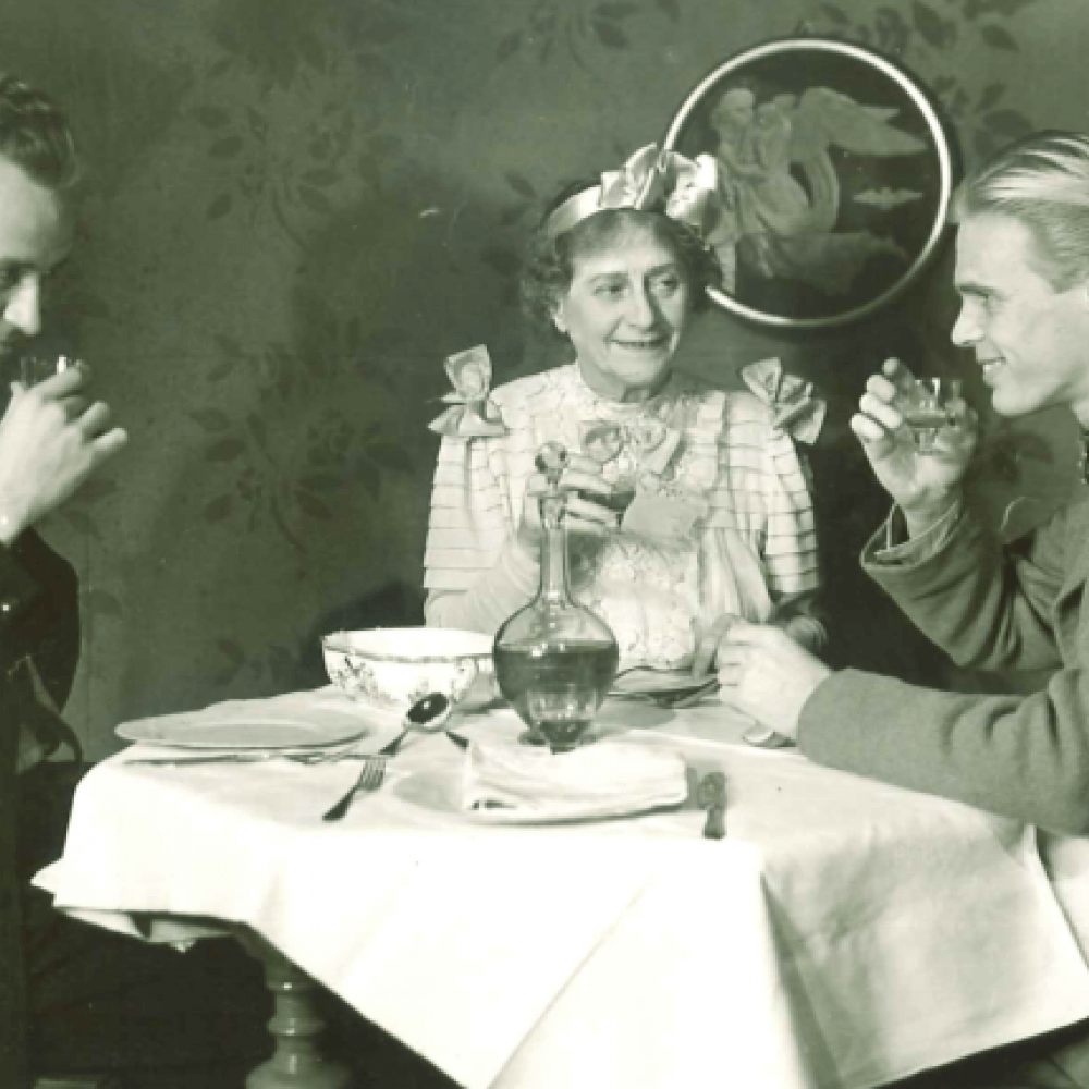 två män och en kvinna ler och dricker runt ett bord