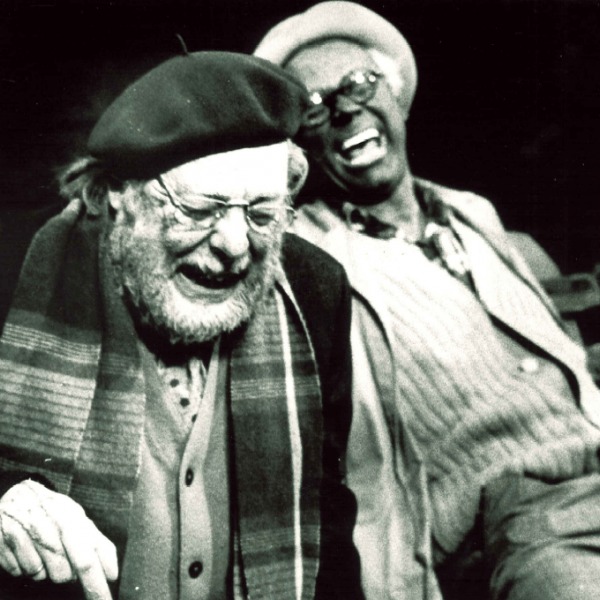 Två män sitter på en bänk och skrattar
