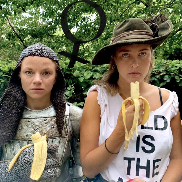 Två unga kvinnor stirrar in i kameran samtidigt som de äter var sin banan.