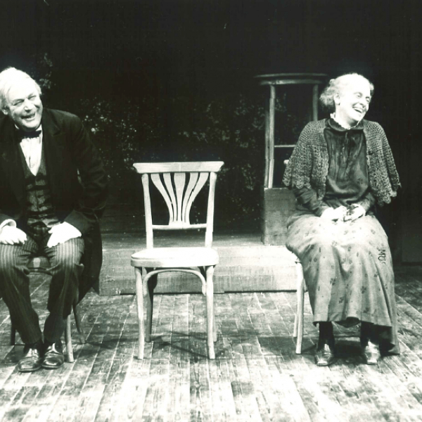 två äldre personer på stolar skrattar